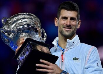 TOPSHOT - Serbia's Novak Djokovic celebrates with the Norman Brookes Challenge Cup trophy following his victory against Greece's Stefanos Tsitsipas in the men's singles final match on day fourteen of the Australian Open tennis tournament in Melbourne on January 29, 2023. (Photo by MANAN VATSYAYANA / AFP) / -- IMAGE RESTRICTED TO EDITORIAL USE - STRICTLY NO COMMERCIAL USE --